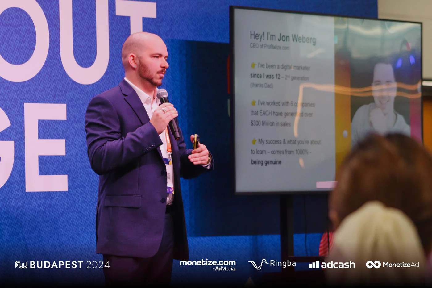 Jon Weberg keynoting at AdWorld Budapest 2024 with the Profitalize.com slide on screen